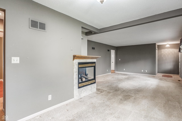 unfurnished living room with carpet floors, a tile fireplace, baseboards, and beam ceiling