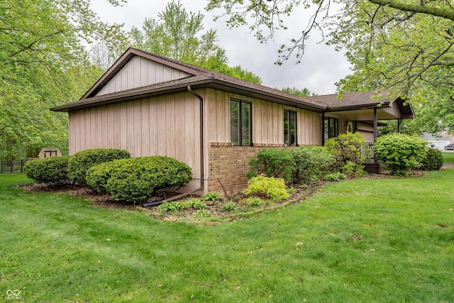 view of side of property featuring a lawn, brick siding, and board and batten siding