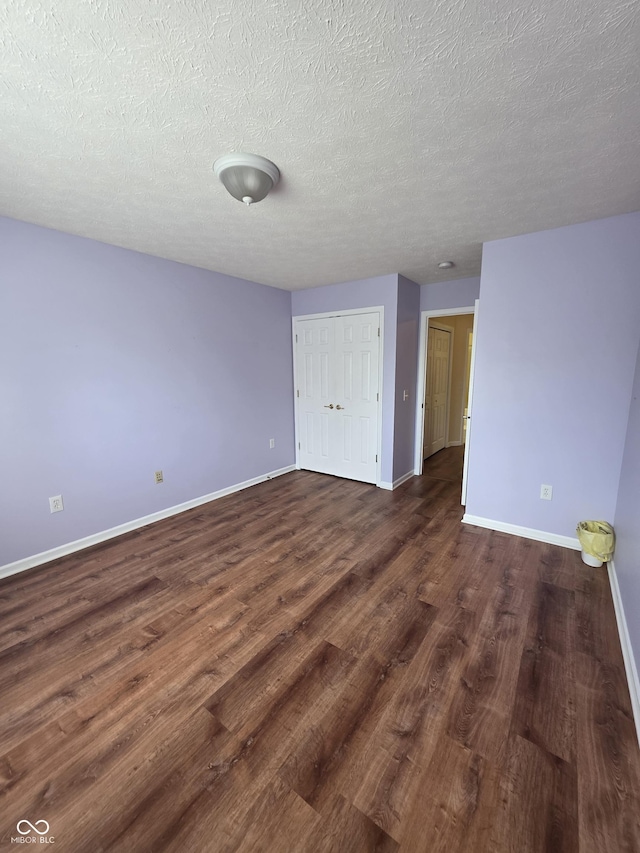 8160 Shores Edge Way, Indianapolis, IN 46237 - unfurnished bedroom featuring baseboards, dark wood finished floors, a closet, and a textured ceiling