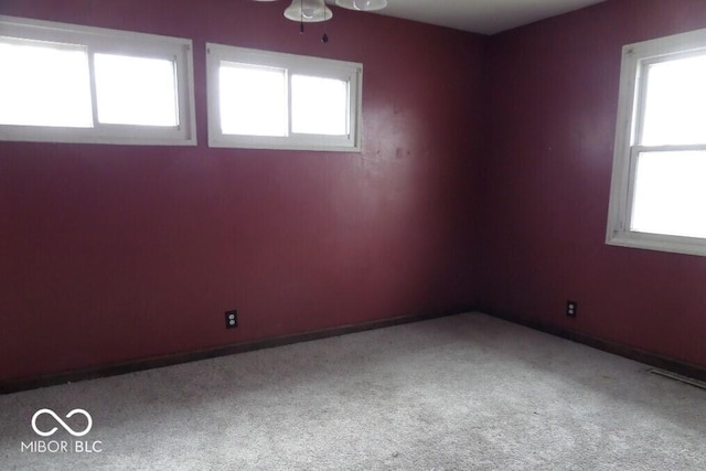 carpeted spare room featuring ceiling fan and baseboards