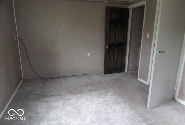 unfurnished room featuring carpet floors and concrete block wall