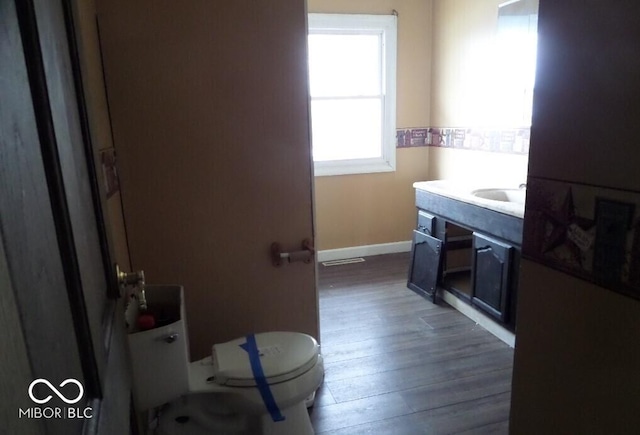 bathroom with toilet, baseboards, vanity, and wood finished floors