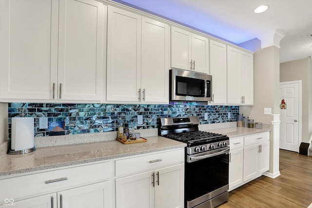 15752 Matthews Ln, Noblesville, IN 46060 - kitchen with decorative backsplash, light stone countertops, light wood-style floors, white cabinets, and appliances with stainless steel finishes