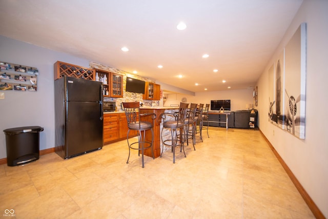 7732 Ashtree Dr, Indianapolis, IN 46259 - kitchen featuring freestanding refrigerator, recessed lighting, a kitchen bar, and brown cabinets