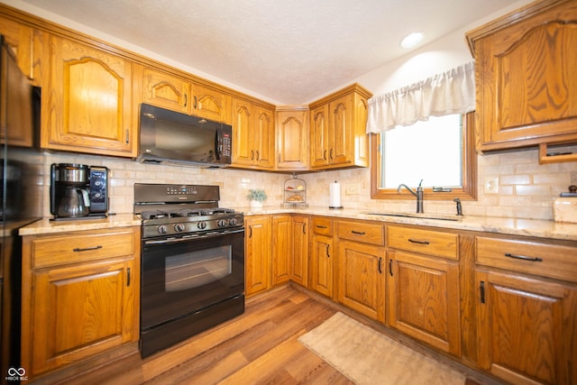 7732 Ashtree Dr, Indianapolis, IN 46259 - kitchen featuring a sink, light stone counters, black appliances, and light wood-type flooring