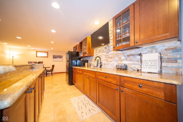 7732 Ashtree Dr, Indianapolis, IN 46259 - kitchen featuring freestanding refrigerator, tasteful backsplash, light stone counters, and brown cabinets