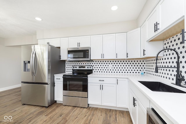 240 E Caven St E, Indianapolis, IN 46225 - kitchen with light countertops, a sink, light wood finished floors, white cabinetry, and appliances with stainless steel finishes