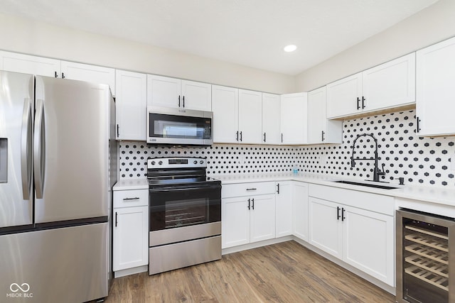 240 E Caven St E, Indianapolis, IN 46225 - kitchen featuring light countertops, wood finished floors, beverage cooler, stainless steel appliances, and decorative backsplash