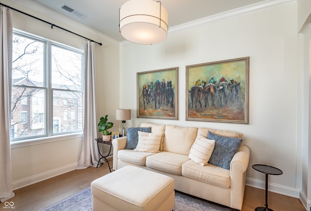 living room featuring wood finished floors, crown molding, baseboards, and visible vents