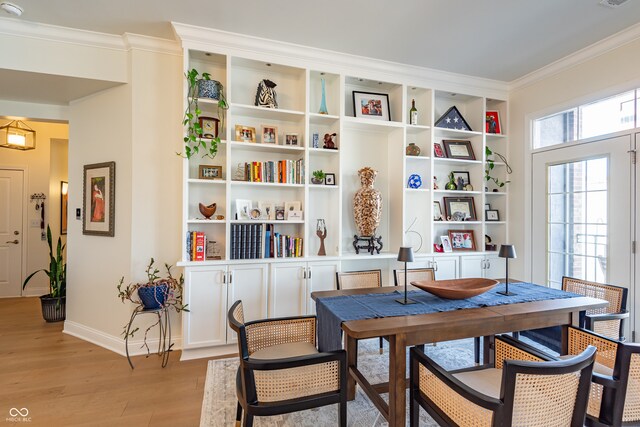 dining room with ornamental molding, baseboards, light wood finished floors, and visible vents