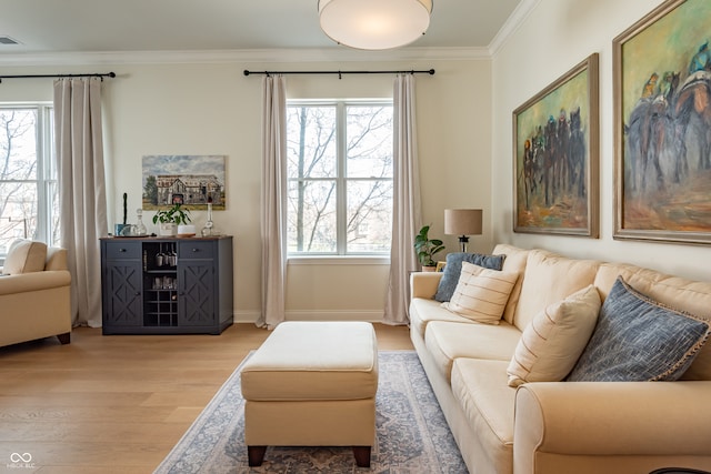 living room with crown molding, baseboards, light wood finished floors, and visible vents