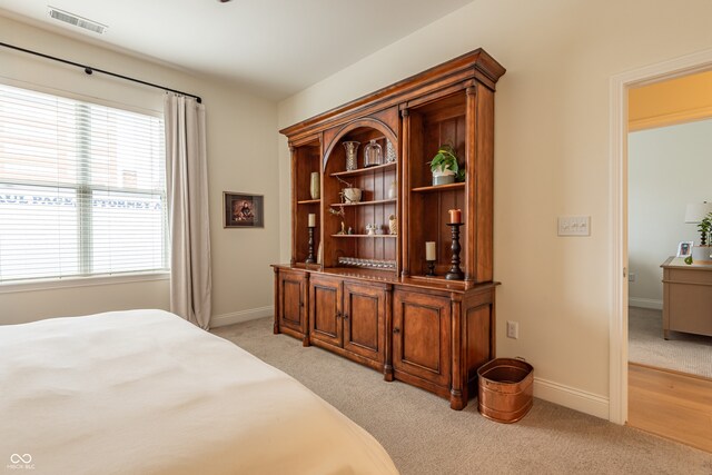 bedroom with baseboards, visible vents, and light colored carpet
