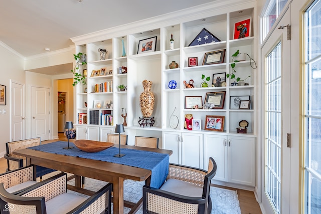 dining room with crown molding and light wood-style flooring
