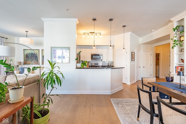 kitchen with backsplash, light wood finished floors, stainless steel appliances, dark countertops, and ornamental molding
