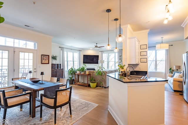 dining room with visible vents, light wood-style floors, ornamental molding, and a ceiling fan
