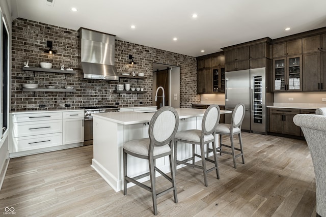 12099 Sigillary Way, Carmel, IN 46032 - kitchen with high quality appliances, wall chimney exhaust hood, light countertops, open shelves, and light wood-style flooring