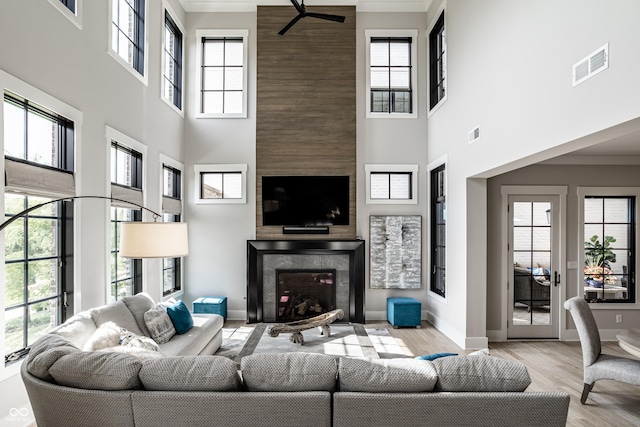 12099 Sigillary Way, Carmel, IN 46032 - living area featuring a towering ceiling, a fireplace, healthy amount of natural light, ceiling fan, and wood finished floors