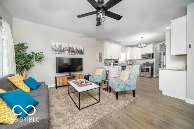 1444 English Ave, Indianapolis, IN 46201 - living area featuring light wood-style flooring, ceiling fan with notable chandelier, baseboards, and recessed lighting