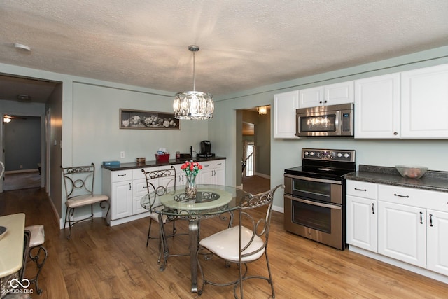 251 Howard Rd, Greenwood, IN 46142 - kitchen with white cabinetry, stainless steel appliances, dark countertops, and light wood finished floors
