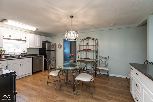 251 Howard Rd, Greenwood, IN 46142 - kitchen with stainless steel appliances, a chandelier, a sink, dark countertops, and wood finished floors