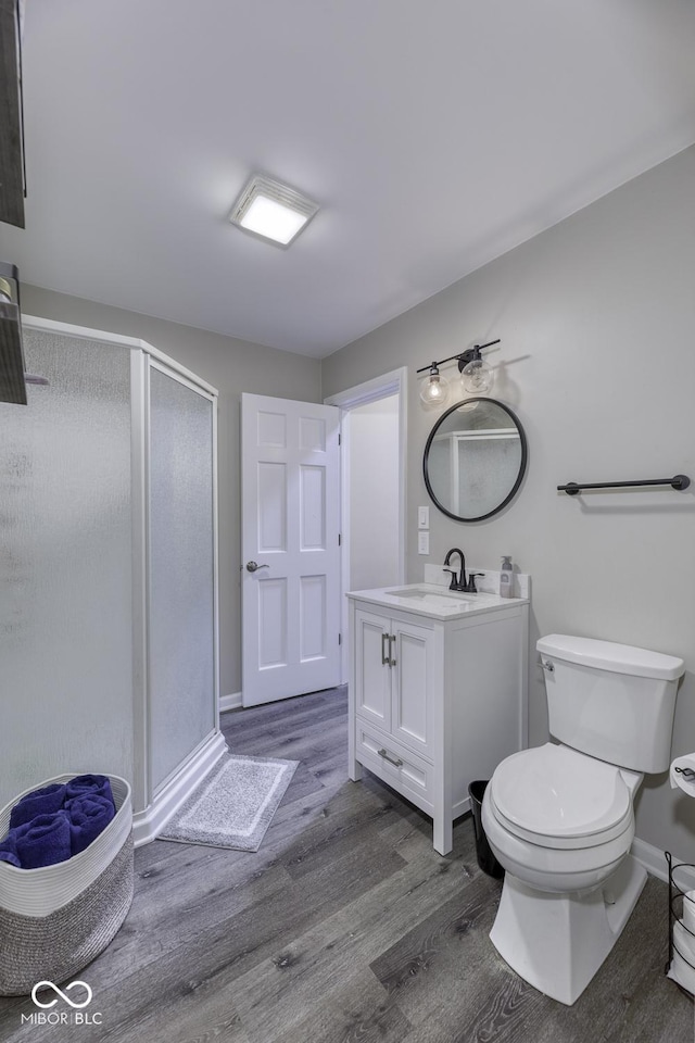 full bathroom featuring toilet, vanity, a shower stall, wood finished floors, and baseboards