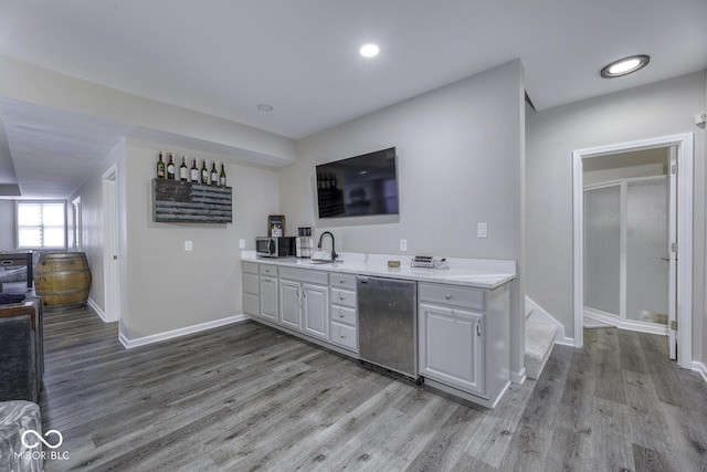 kitchen with light wood finished floors, baseboards, light countertops, and appliances with stainless steel finishes
