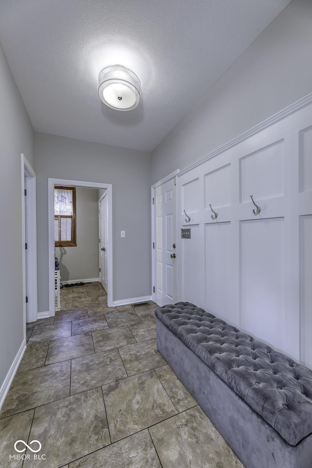 mudroom featuring baseboards and a textured ceiling