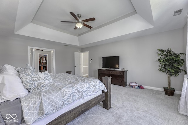 bedroom with a tray ceiling, carpet floors, a spacious closet, baseboards, and visible vents