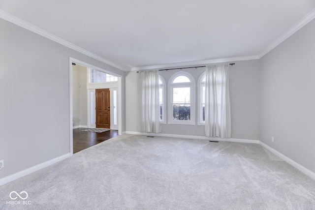 carpeted empty room featuring crown molding, baseboards, and visible vents
