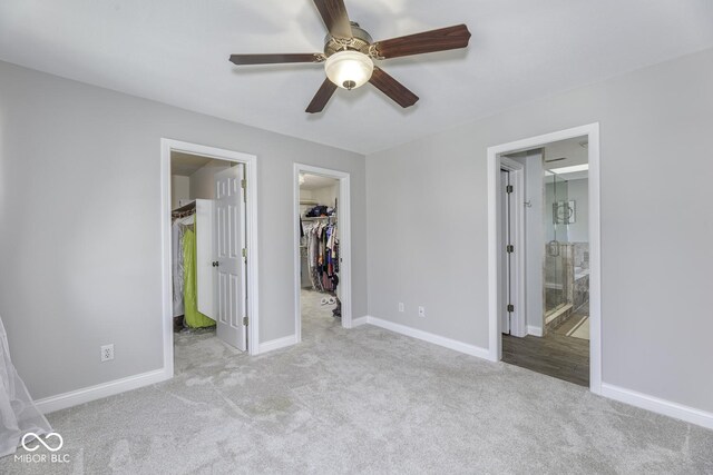 unfurnished bedroom with a spacious closet, carpet, a closet, and baseboards
