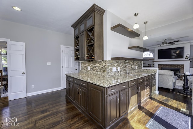 kitchen with backsplash, a ceiling fan, light stone countertops, dark wood-type flooring, and dark brown cabinets