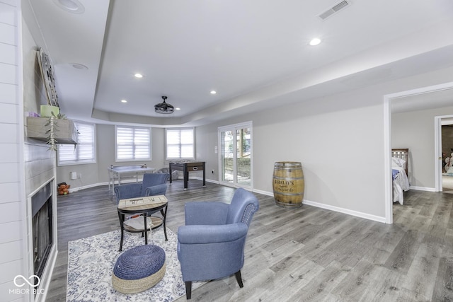 living room with recessed lighting, baseboards, a raised ceiling, visible vents, and wood finished floors