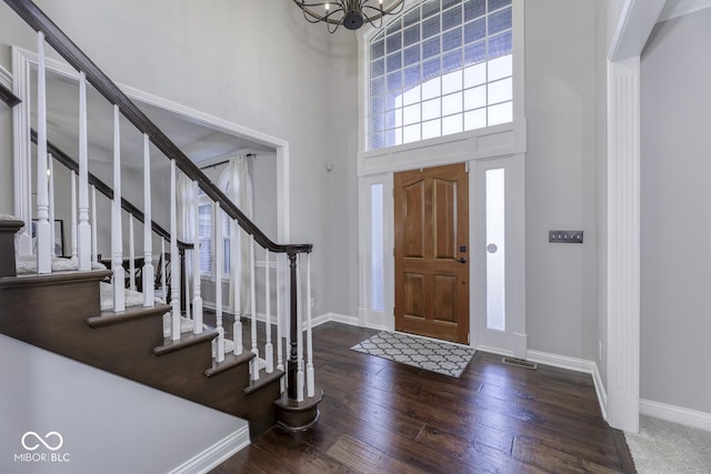 foyer entrance with hardwood / wood-style floors, baseboards, a high ceiling, and an inviting chandelier