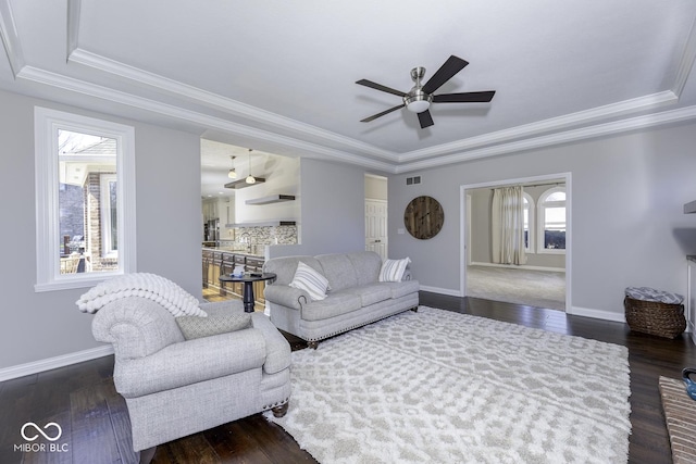 living room featuring dark wood finished floors, crown molding, a ceiling fan, and a raised ceiling