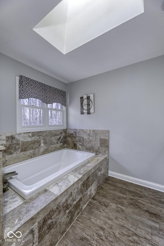 bathroom featuring baseboards, wood finished floors, and a garden tub