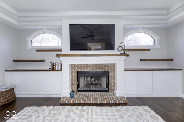 unfurnished living room with a healthy amount of sunlight, dark wood-style floors, crown molding, and a brick fireplace
