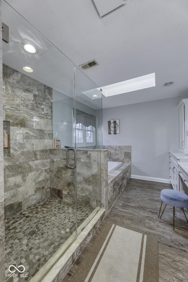 bathroom with visible vents, a shower stall, baseboards, wood finished floors, and a garden tub