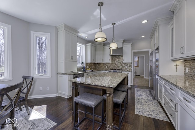 kitchen with a kitchen island, dark wood-style flooring, a sink, and a breakfast bar area