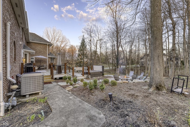view of yard featuring an outdoor fire pit, a deck, and central AC