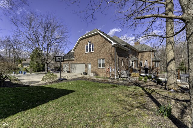 rear view of property featuring concrete driveway, a chimney, an attached garage, brick siding, and a lawn
