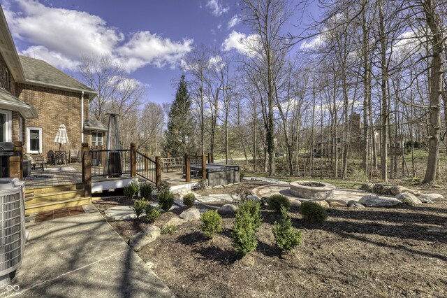 view of yard with central air condition unit, an outdoor fire pit, and a deck