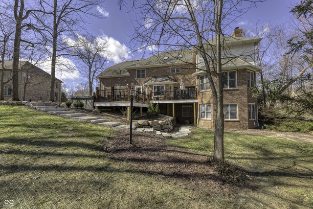 back of property with a yard, brick siding, a deck, and a chimney