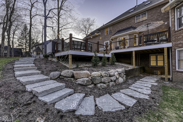 rear view of house featuring stairs, a wooden deck, and brick siding