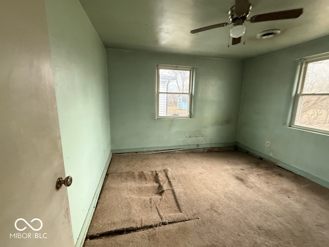 carpeted empty room with a ceiling fan and baseboards