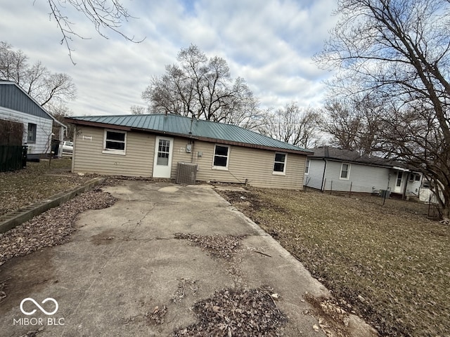 back of property featuring driveway and metal roof