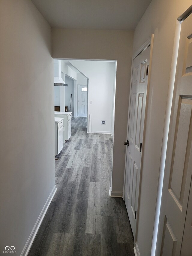 hallway featuring dark wood-style flooring and baseboards