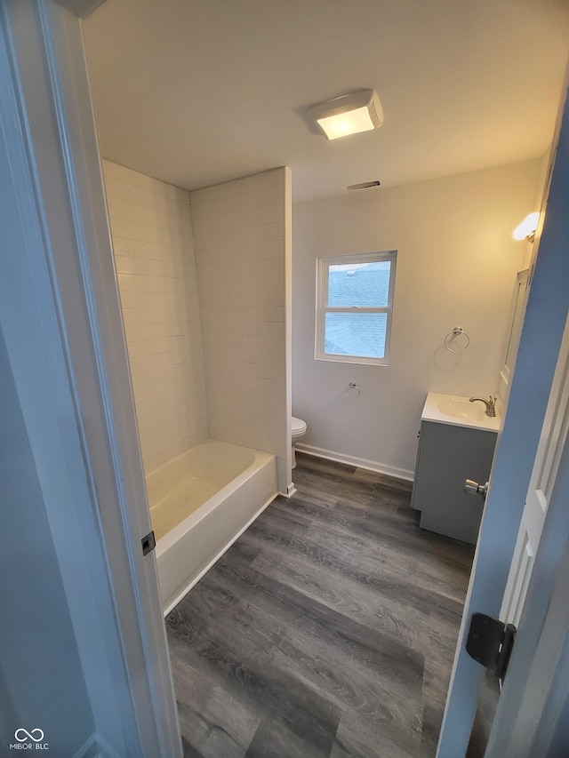 full bath featuring toilet, vanity, baseboards, and wood finished floors