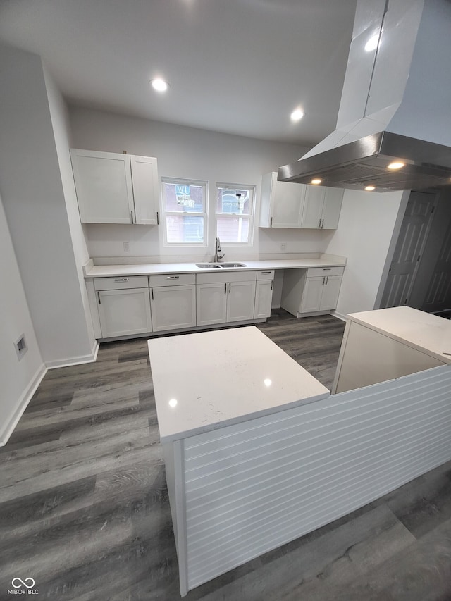 kitchen with light countertops, island exhaust hood, baseboards, a sink, and dark wood-style floors