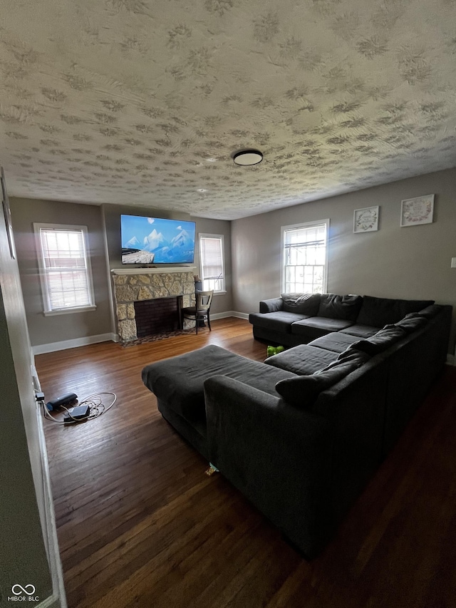 living area featuring a wealth of natural light, baseboards, a fireplace, and wood finished floors