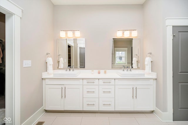 full bathroom with double vanity, tile patterned flooring, baseboards, and a sink